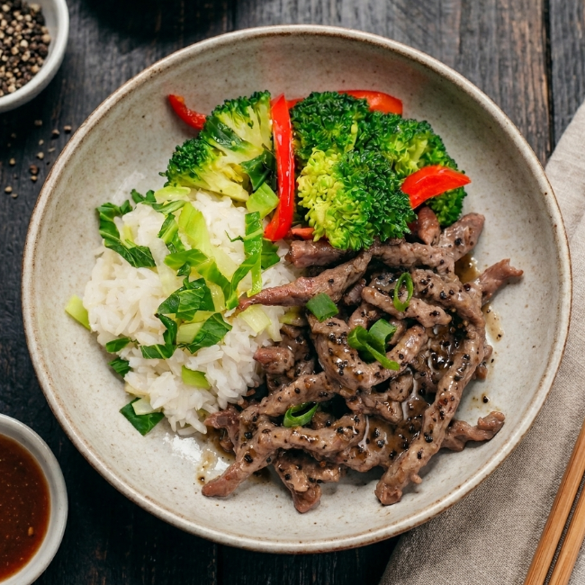 Fittery signature black pepper beef rump with Chinese greens and Shanghai vegetable rice, served on a plate.