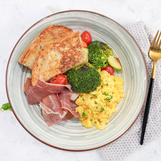 炒蛋配帕瑪火腿、烤蔬菜和小麥麵包