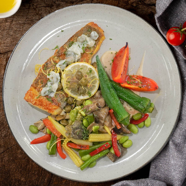 Signature meal of grilled barramundi with lemon capers and vegetables, served with a side of starch.