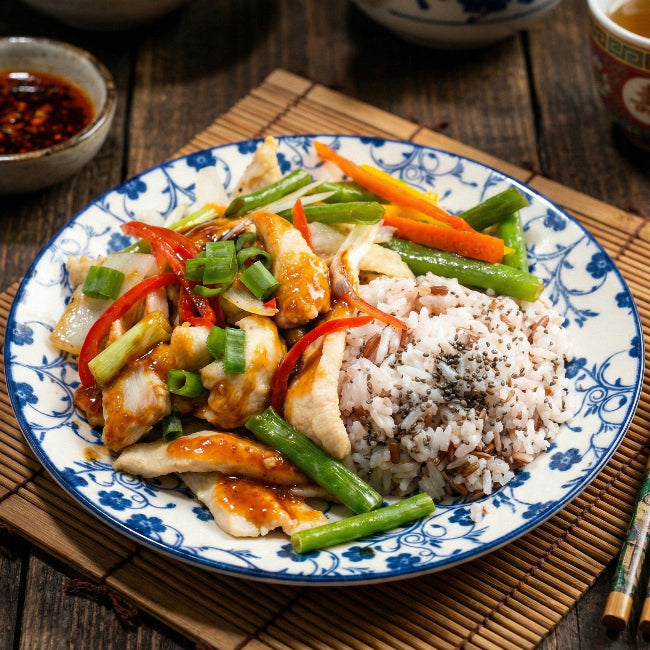 Signature Fittery scallion ginger chicken claypot with stir-fried vegetables and flaxseed rice on a plate.
