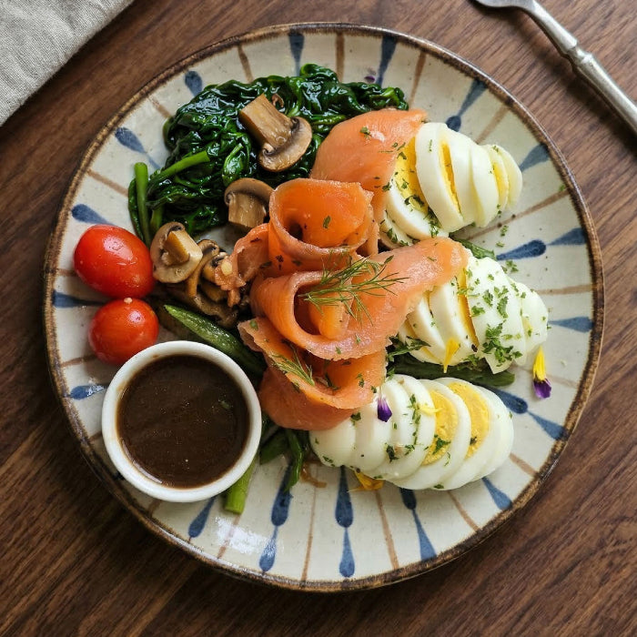 Fittery smoked salmon energy bowl with eggs, balsamic honey dressing, and side salad on a plate.