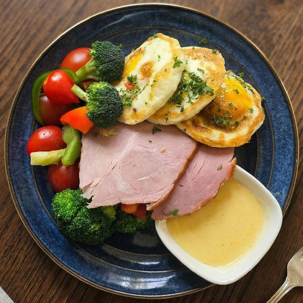 Fittery signature baked eggs and ham breakfast with cream cheese and side salad on a plate, served for a hearty morning meal.